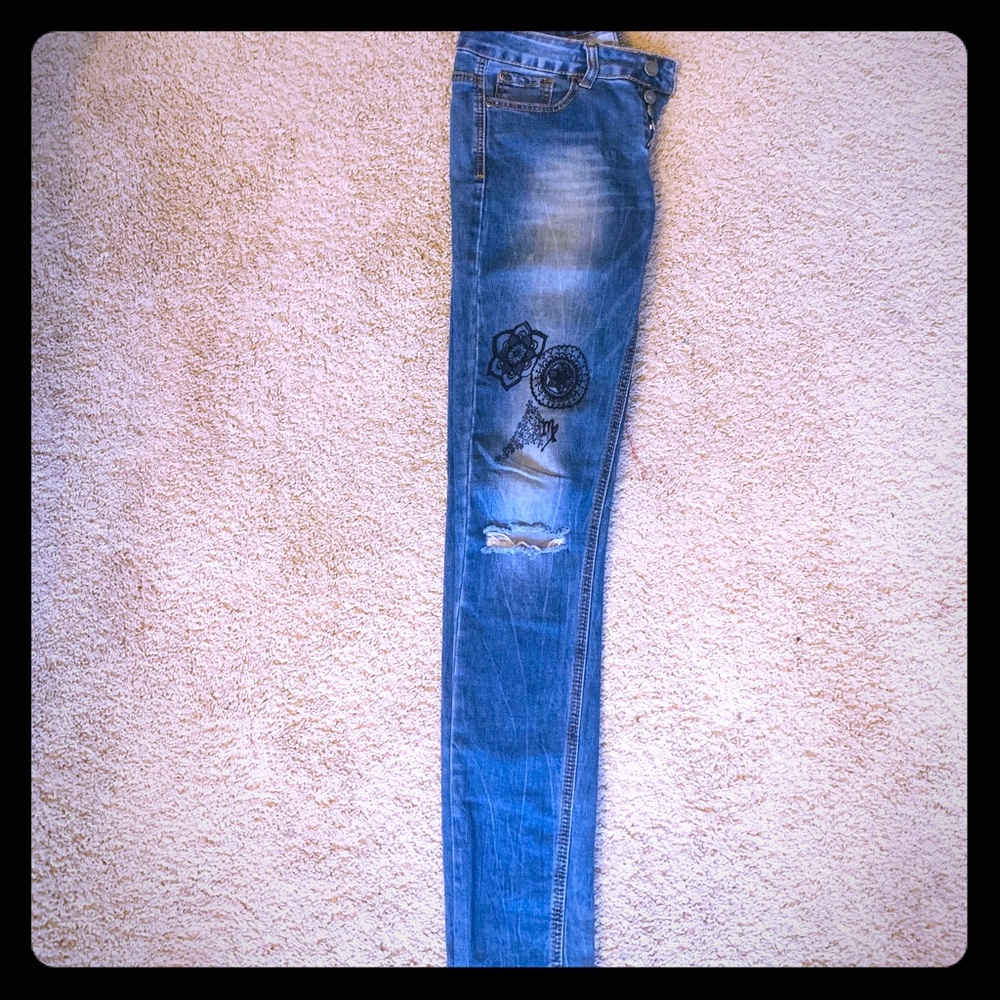 Skinny blue jeans with flower design on pant leg.